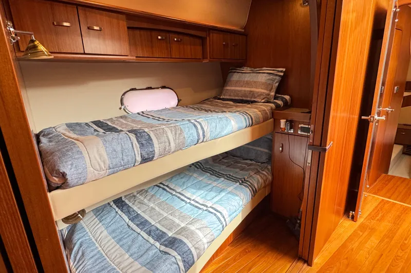 Slide: The Image of 2014 Tiara Yachts 5800 Sovran cabin with wooden interior and bunk beds. - 45
