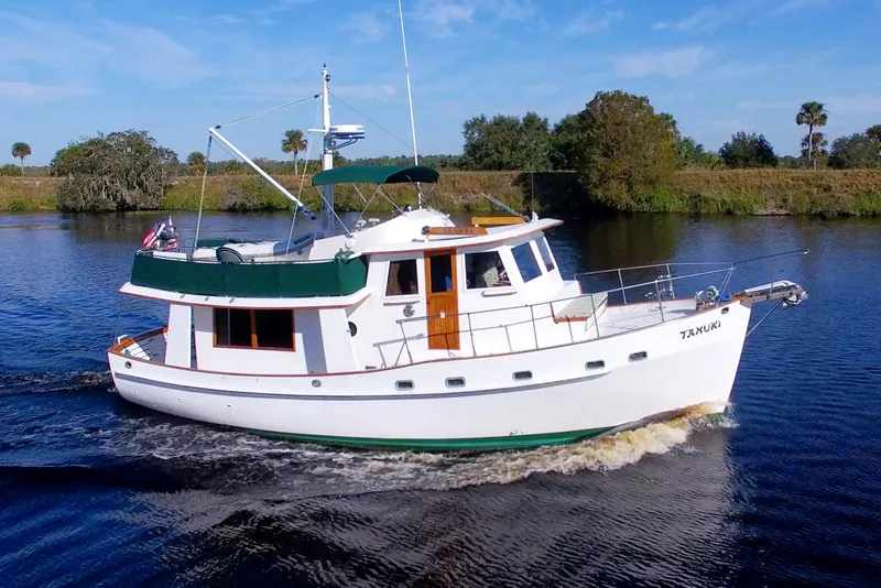 The Image of 1980 Kadey-Krogen 42 trawler cruising on a calm river under a clear blue sky. - 0
