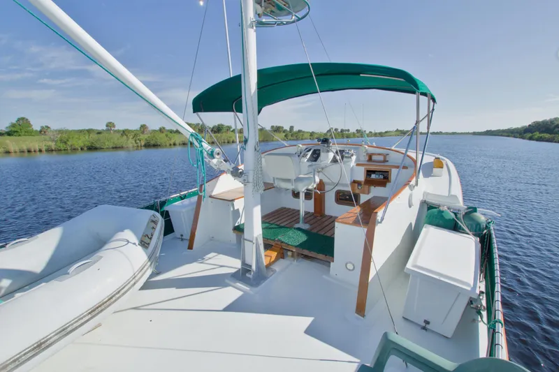 Slide: The Image of 1980 Kadey-Krogen 42 trawler on a serene river, featuring a spacious deck and green canopy. - 10