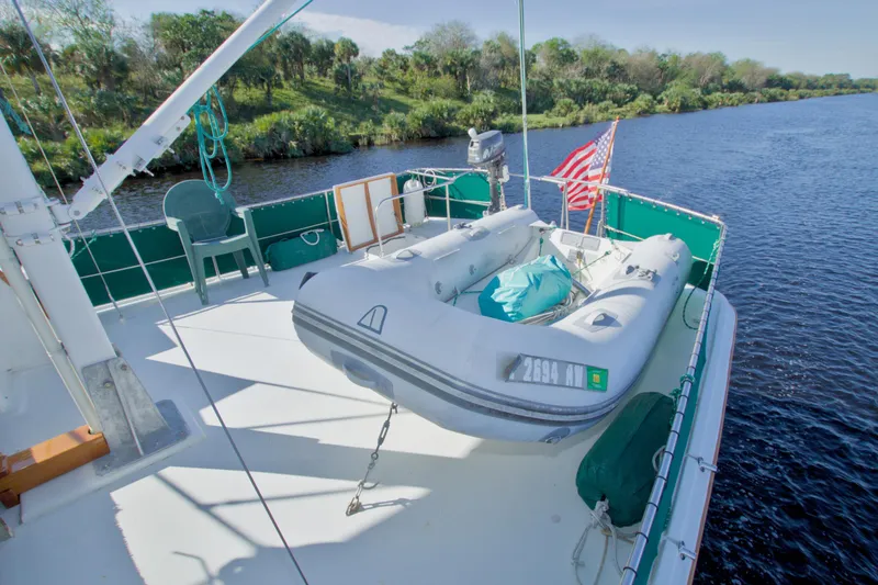 Slide: The Image of 1980 Kadey-Krogen 42 trawler with inflatable dinghy on deck, cruising a scenic river. - 15