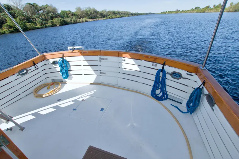 Slide: The Image of 1980 Kadey-Krogen 42 trawler deck with ropes, cruising on a serene river. - 17