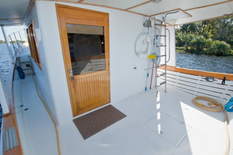 Slide: The Image of 1980 Kadey-Krogen 42 trawler deck with wooden door, ladder, and scenic water view. - 18