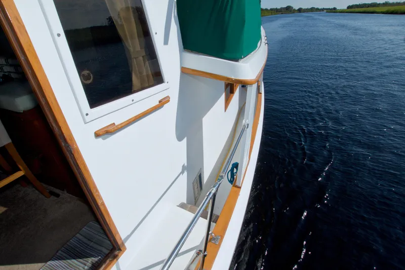 Slide: The Image of 1980 Kadey-Krogen 42 trawler cruising on a calm river, showcasing its deck and railing. - 19