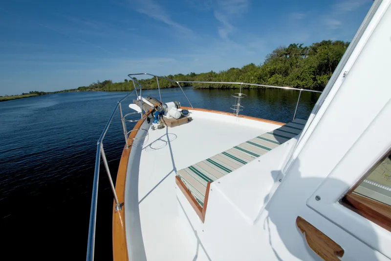 Slide: The Image of 1980 Kadey-Krogen 42 trawler cruising on a serene river with lush greenery. - 22