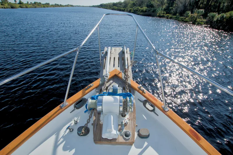 Slide: The Image of Kadey-Krogen 42 trawler (1980) cruising on a sunlit river, surrounded by lush greenery. - 23