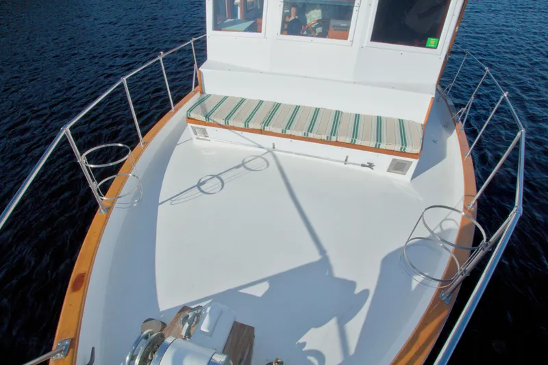 Slide: The Image of 1980 Kadey-Krogen 42 trawler deck with striped bench, surrounded by water. - 24