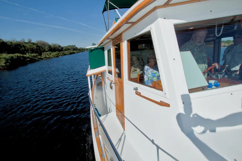 Slide: The Image of 1980 Kadey-Krogen 42 trawler cruising on a scenic river with passengers onboard. - 26