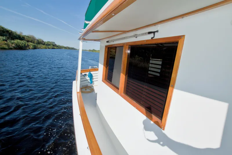 Slide: The Image of 1980 Kadey-Krogen 42 trawler cruising on a serene river with lush greenery. - 27