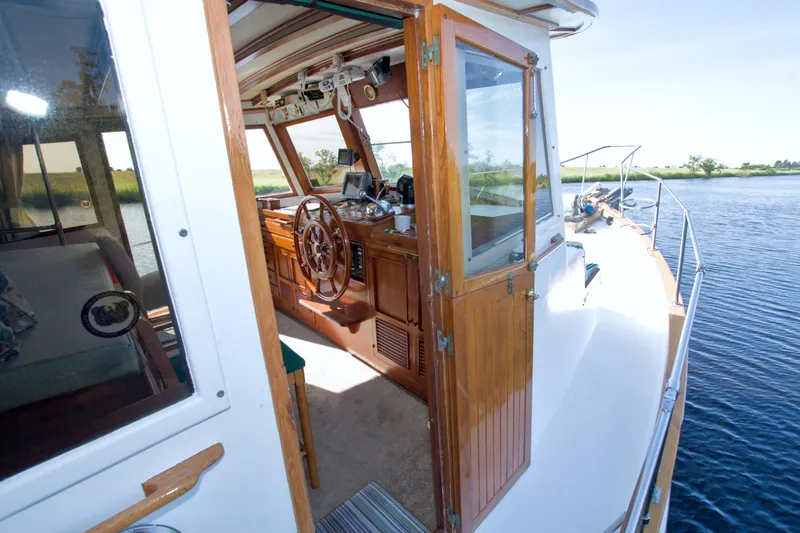 Slide: The Image of 1980 Kadey-Krogen 42 trawler interior with wooden helm and open cabin door. - 29