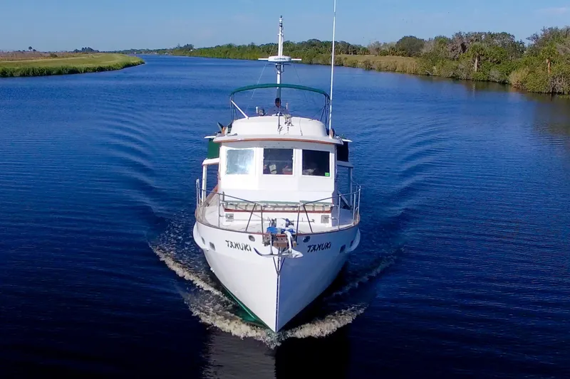 Slide: The Image of 1980 Kadey-Krogen 42 trawler cruising on a serene river under clear skies. - 5