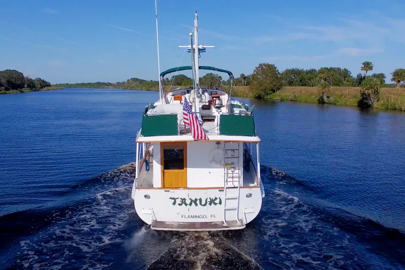 Slide: The Image of 1980 Kadey-Krogen 42 trawler cruising on a scenic river with American flag. - 6