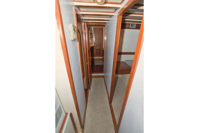 Slide: The Image of Narrow hallway inside 1980 Kadey-Krogen 42 trawler, featuring wooden trim and carpeted floor. - 60