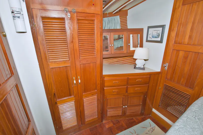 Slide: The Image of 1980 Kadey-Krogen 42 trawler interior with wooden cabinets and dresser, featuring a lamp and framed artwork. - 63