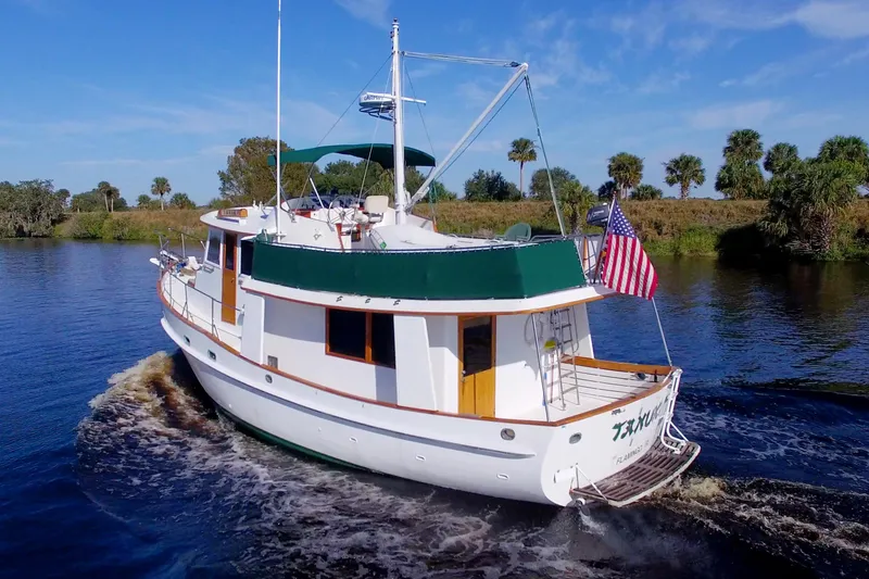 Slide: The Image of 1980 Kadey-Krogen 42 trawler cruising on a scenic river with American flag. - 7