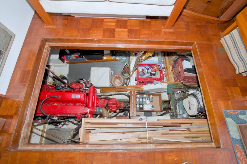 Slide: The Image of Engine room of a 1980 Kadey-Krogen 42 trawler with visible red engine and storage. - 73