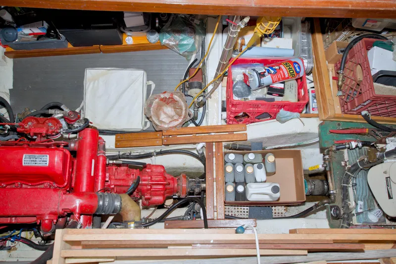 Slide: The Image of Engine room of a 1980 Kadey-Krogen 42 trawler with red engine and storage items. - 74