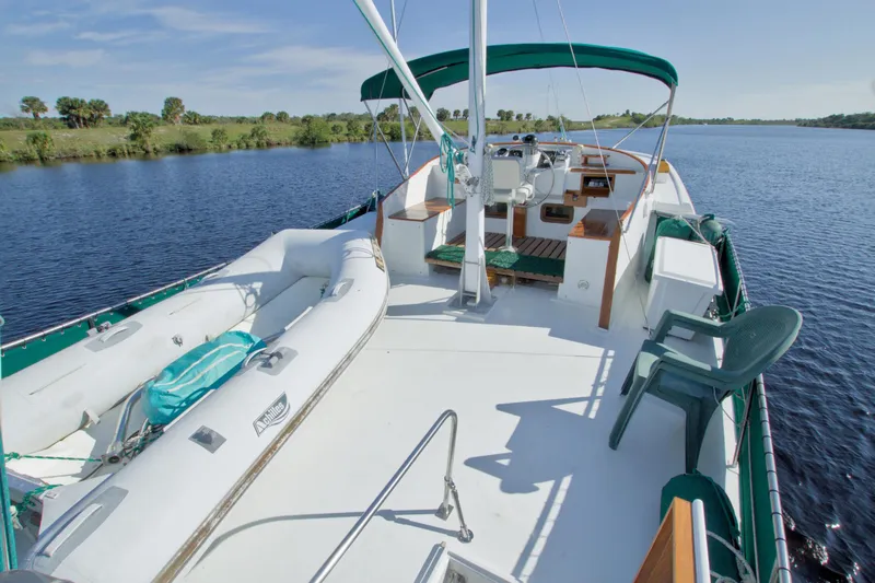 Slide: The Image of 1980 Kadey-Krogen 42 trawler on serene water, featuring spacious deck and inflatable dinghy. - 9
