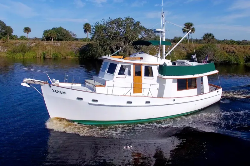 Slide: The Image of 1980 Kadey-Krogen 42 trawler cruising on a scenic river with lush greenery. - 96