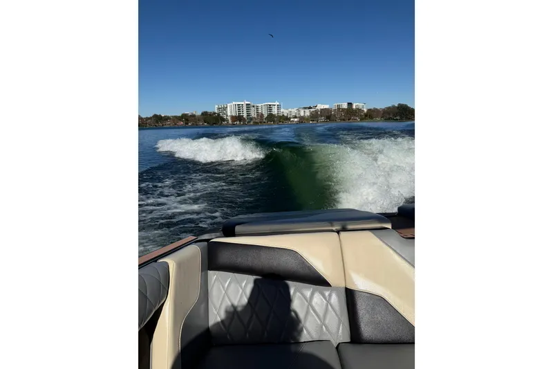 Slide: The Image of 2022 Tigé Z1 boat creating wake on a sunny lake with cityscape background. - 8
