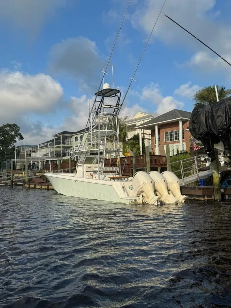 Slide: The Image of 2012 Contender 39ST boat docked by waterfront homes under a blue sky. - 2