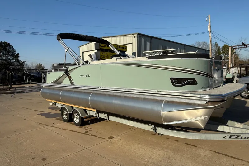 Slide: The Image of 2026 Avalon LSZ Quad Lounger Shift pontoon boat on trailer, outdoor dealership setting. - 3