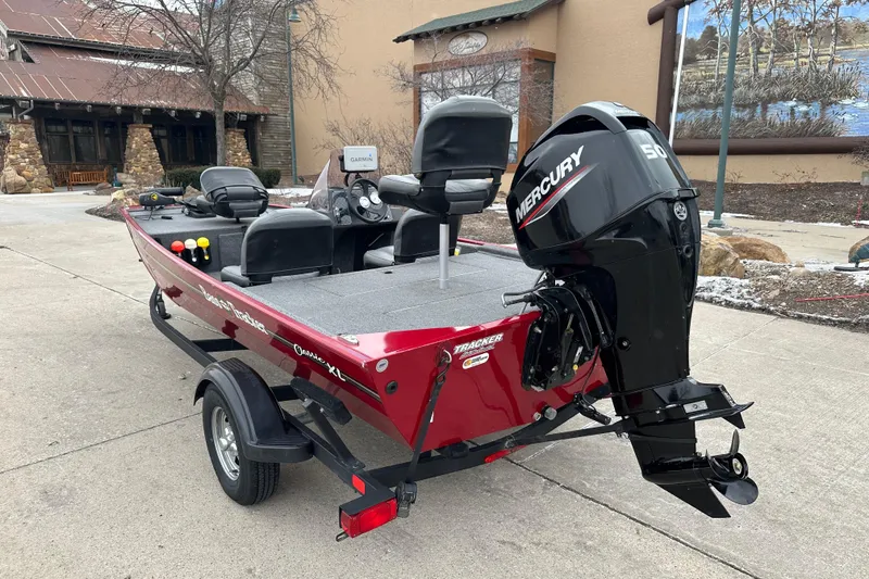 Slide: The Image of 2024 Tracker Bass Tracker Classic XL boat with Mercury engine, parked outdoors. - 2