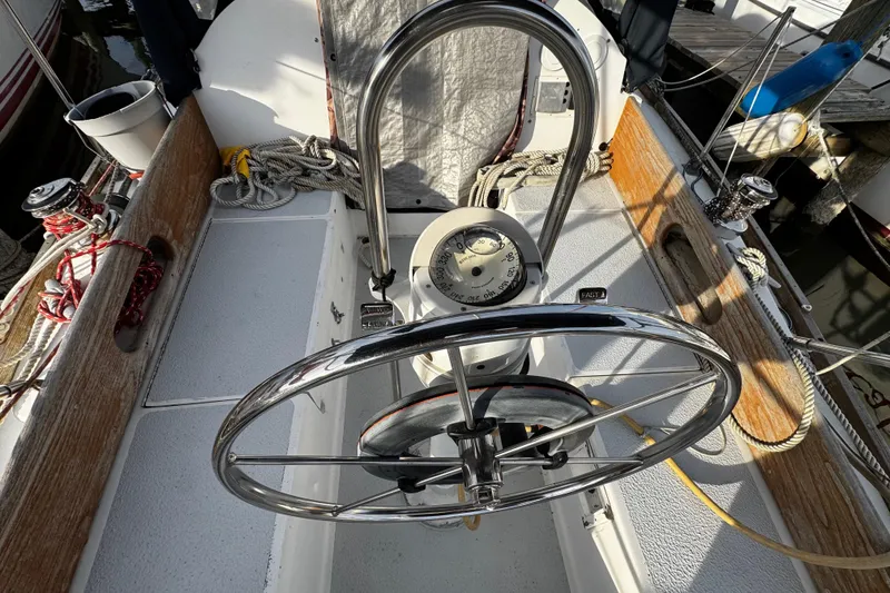 Slide: The Image of 1977 Bristol 29.9 sailboat cockpit with steering wheel and compass, docked at marina. - 12
