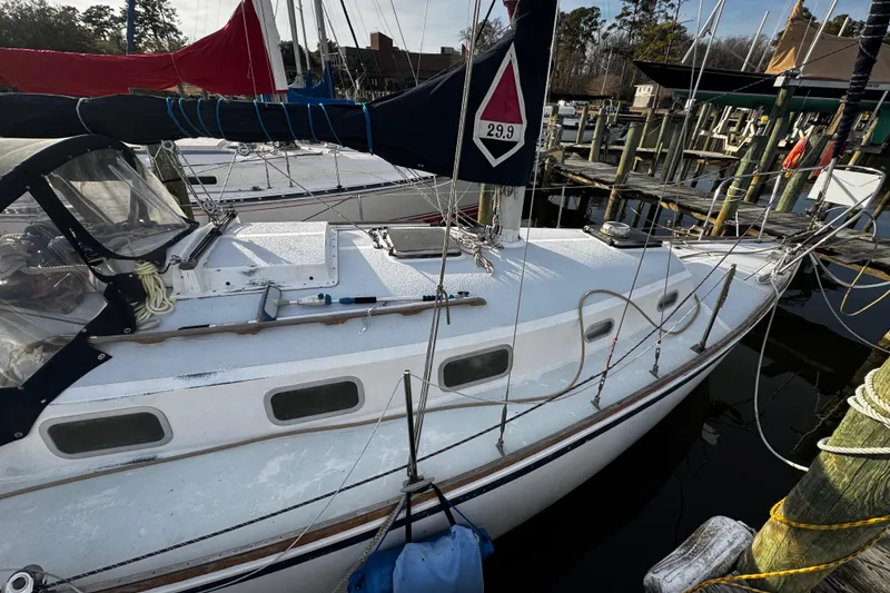 Slide: The Image of 1977 Bristol 29.9 sailboat docked at marina, featuring sleek white design and rigging. - 2