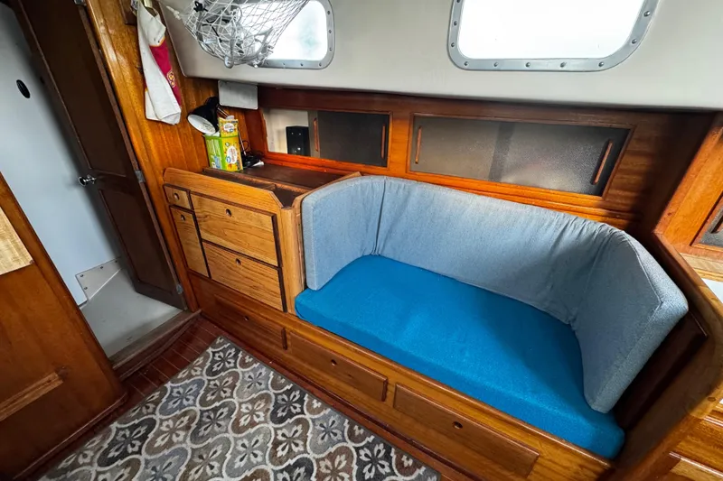 Slide: The Image of Interior of a 1977 Bristol 29.9 sailboat with wooden cabinetry and blue cushioned seating. - 49