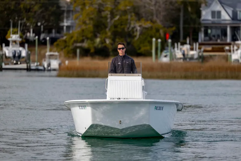 Slide: The Image of Man piloting 2025 Intruder 23 boat on calm water near docks. - 10