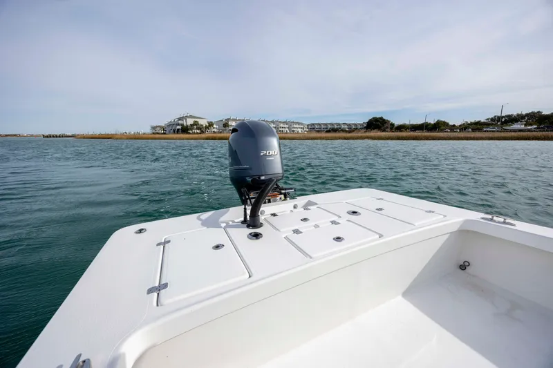 Slide: The Image of 2025 Intruder 23 boat with outboard motor on calm water, distant shoreline view. - 12