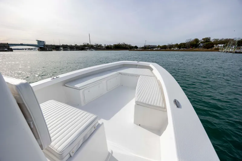 Slide: The Image of 2025 Intruder 23 boat with white seating, cruising on calm waters near a bridge. - 19