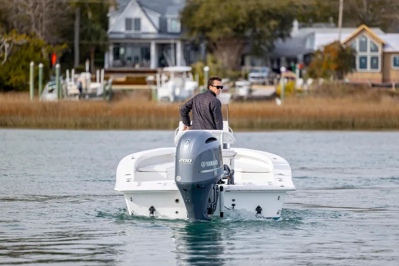 Slide: The Image of Man steering 2025 Intruder 23 boat with Yamaha engine on calm water. - 4