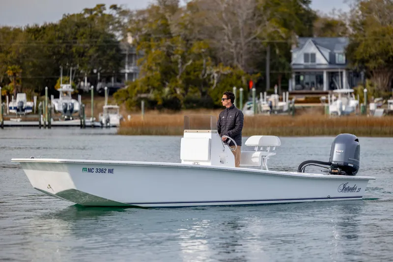 Slide: The Image of 2025 Intruder 23 boat on water with person steering, scenic background. - 8