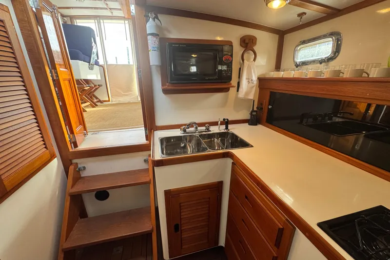 Slide: The Image of 2001 Ellis 36 Flybridge yacht kitchen with wooden cabinetry, sink, and microwave. - 21