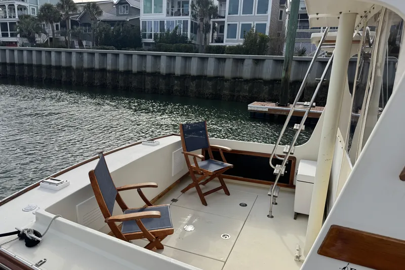 Slide: The Image of 2001 Ellis 36 Flybridge boat deck with chairs, docked near waterfront homes. - 48