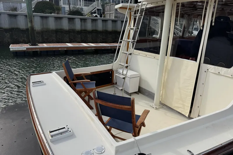 Slide: The Image of 2001 Ellis 36 Flybridge boat with deck chairs and ladder, docked by waterfront. - 49