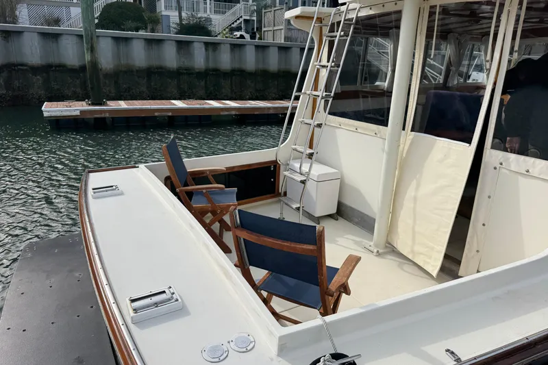Slide: The Image of 2001 Ellis 36 Flybridge boat with chairs on deck, docked by waterfront. - 50