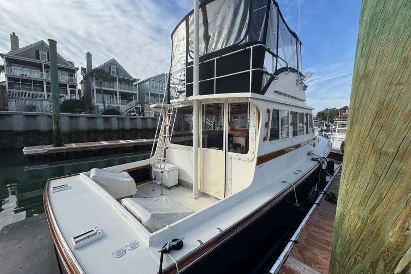 Slide: The Image of 2001 Ellis 36 Flybridge yacht docked near waterfront homes, showcasing elegant design. - 6