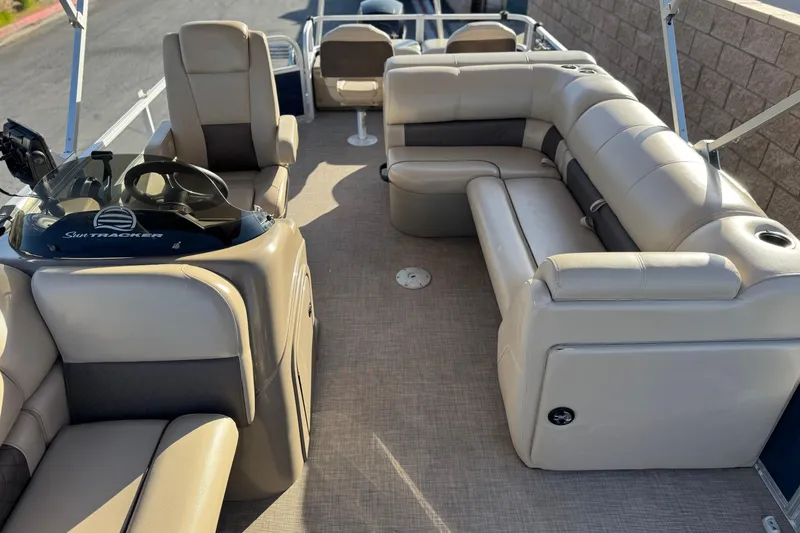 Slide: The Image of 2022 Sun Tracker Fishin' Barge 22 DLX interior with beige seating and steering console. - 17