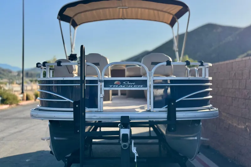 Slide: The Image of 2022 Sun Tracker Fishin' Barge 22 DLX pontoon boat, parked with scenic mountain backdrop. - 2