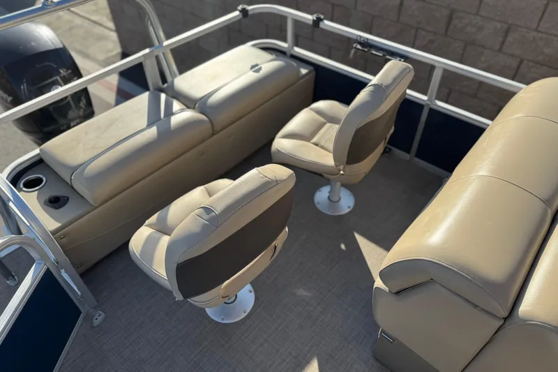 Slide: The Image of 2022 Sun Tracker Fishin' Barge 22 DLX interior with beige seating and cup holders. - 24