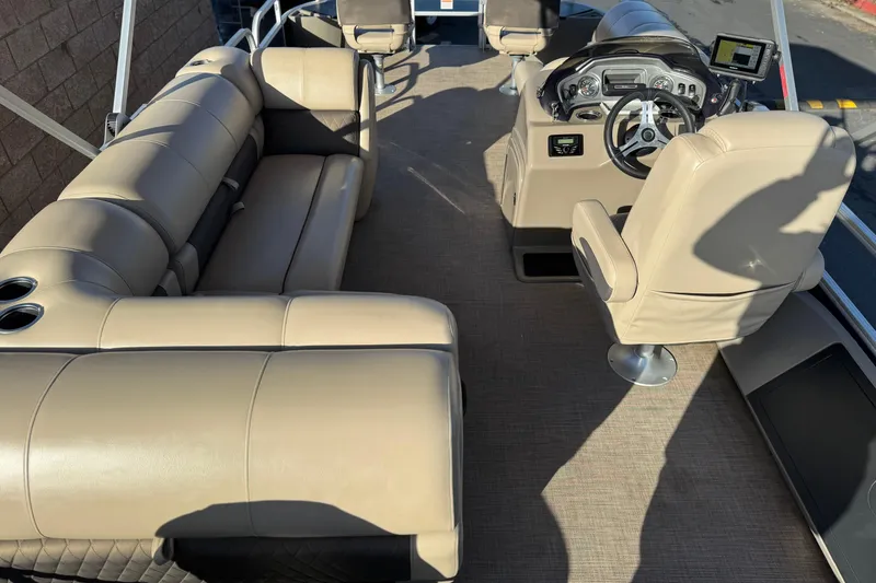 Slide: The Image of 2022 Sun Tracker Fishin' Barge 22 DLX interior with beige seating and steering console. - 28
