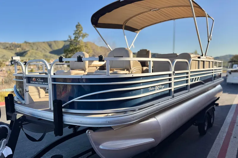 Slide: The Image of 2022 Sun Tracker Fishin' Barge 22 DLX pontoon boat with canopy, parked on trailer. - 3