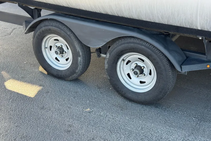 Slide: The Image of Trailer wheels of a 2022 Sun Tracker Fishin' Barge 22 DLX on pavement. - 34
