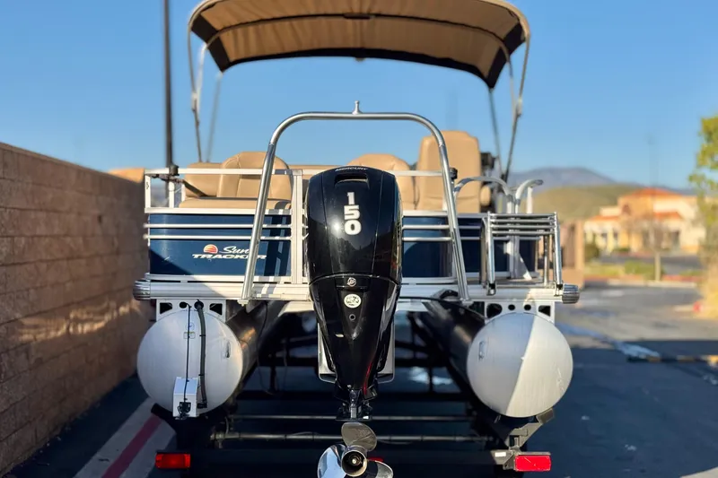 Slide: The Image of 2022 Sun Tracker Fishin' Barge 22 DLX pontoon boat with 150 HP motor, parked outdoors. - 5