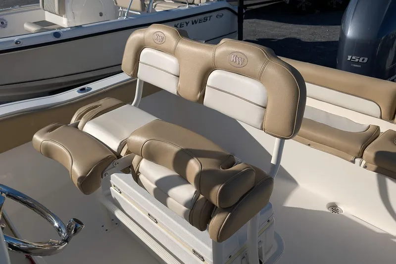 Slide: The Image of 2016 Key West 219 FS boat interior with tan cushioned seating and steering wheel. - 12