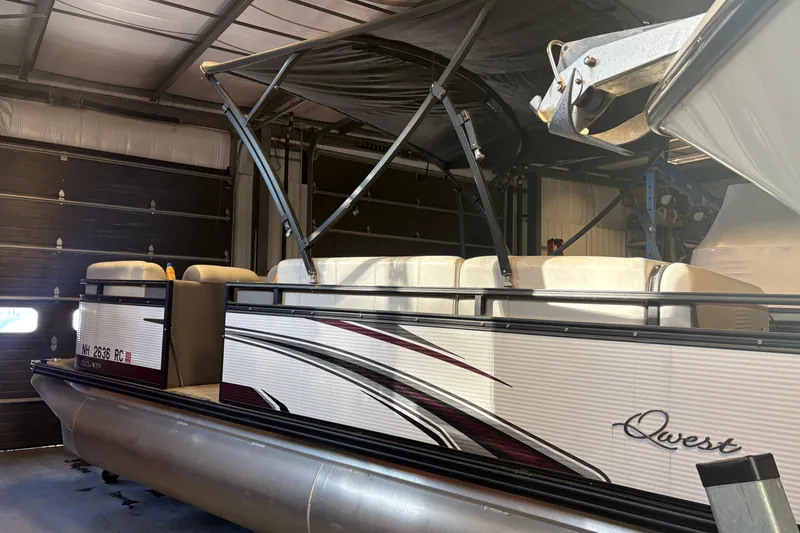 Slide: The Image of 2023 Qwest Lanai 820 pontoon boat in a garage, featuring sleek design and comfortable seating. - 2
