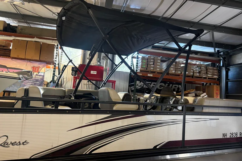 Slide: The Image of 2023 Qwest Lanai 820 pontoon boat in a storage facility with canopy and seating. - 6