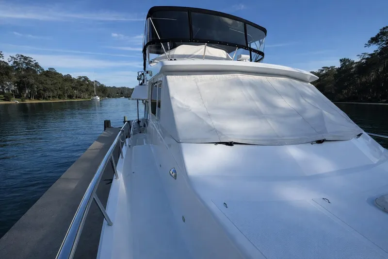 Slide: The Image of 2003 Altima 55 Pilothouse yacht on calm water, surrounded by trees. - 2